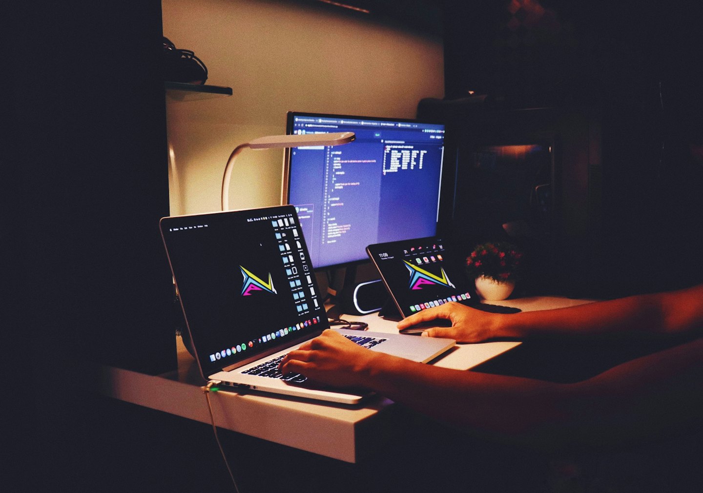 Mani che digitano su un laptop accanto a un tablet su una scrivania.